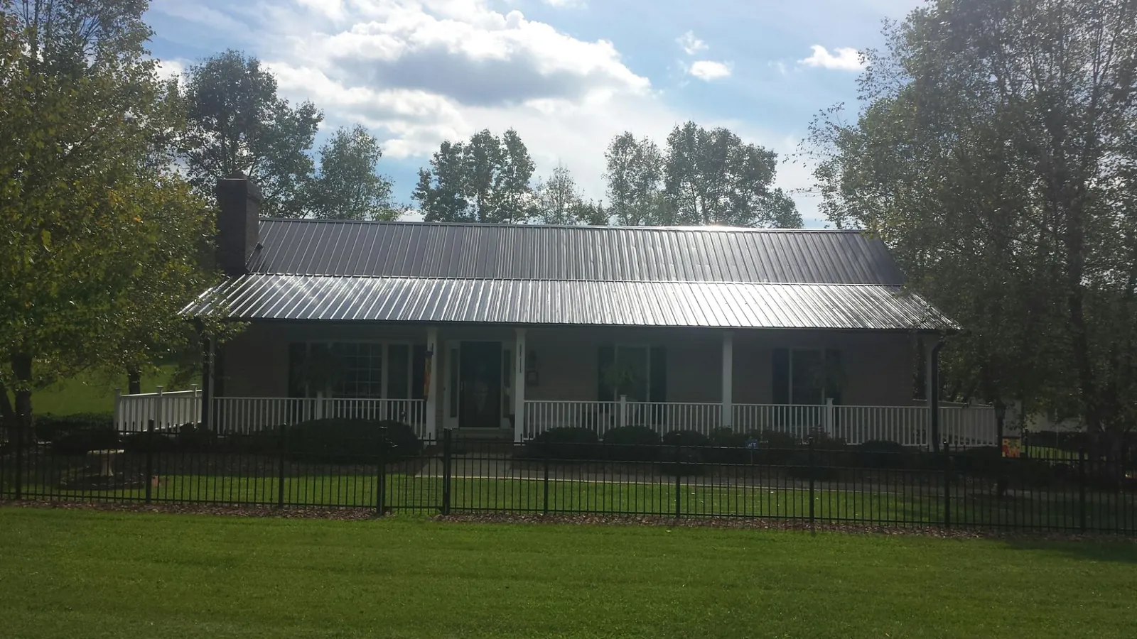 Gray metal roof on a brick ranch with a full width front porch — Gutter Guard Installation work by our crew in Plantersville