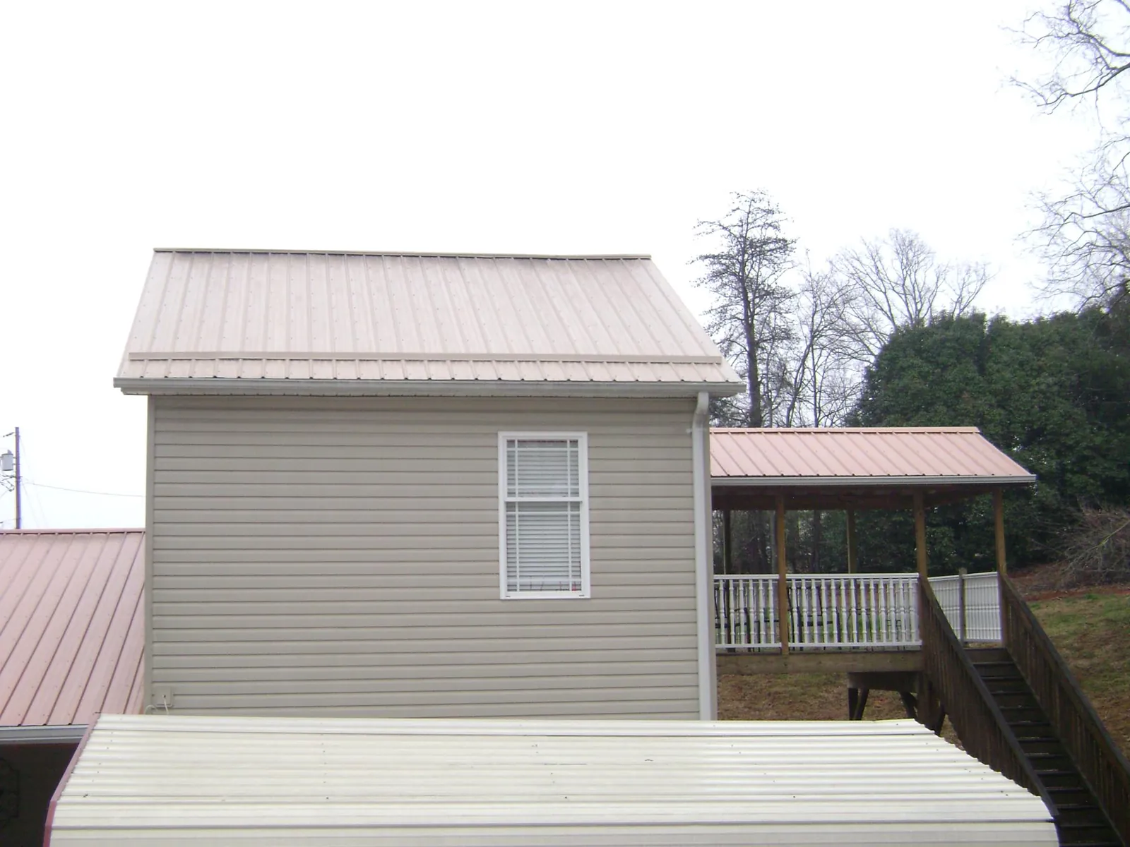 Tan metal roofs on a two story addition and attached porch, from a Roof Replacement job in Plantersville