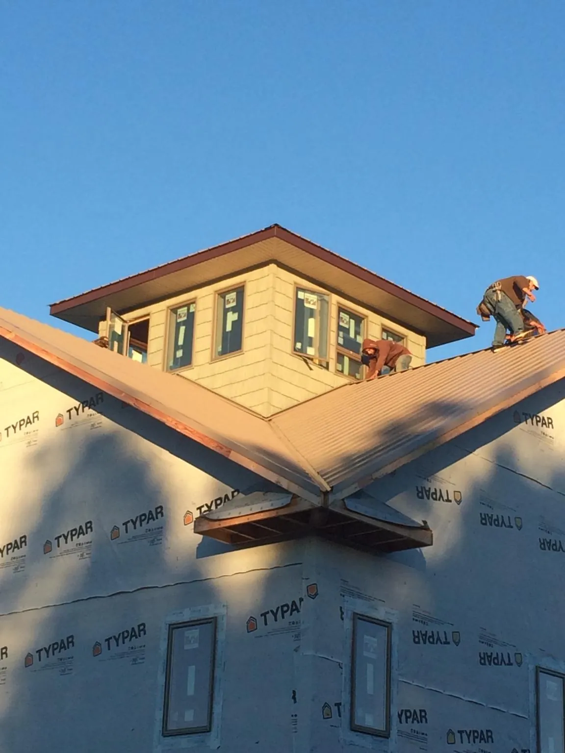 Roofers working around a rooftop cupola on a new metal roof at sunset — Roof Waterproofing in Plantersville by Roofing Brothers